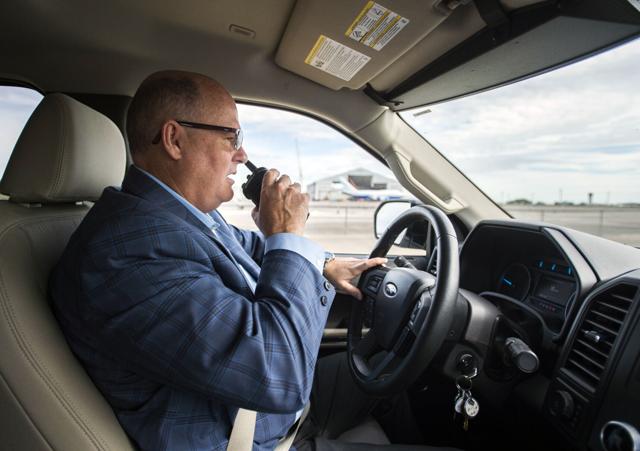 Airport Executive Director Kevin Melton communicates with other airport staff on a walkie talkie as he drives through the airport grounds Wednesday, November 10, 2021, at Chennault International Airport in Lake Charles, La. STAFF PHOTO BY LESLIE WESTBROOK